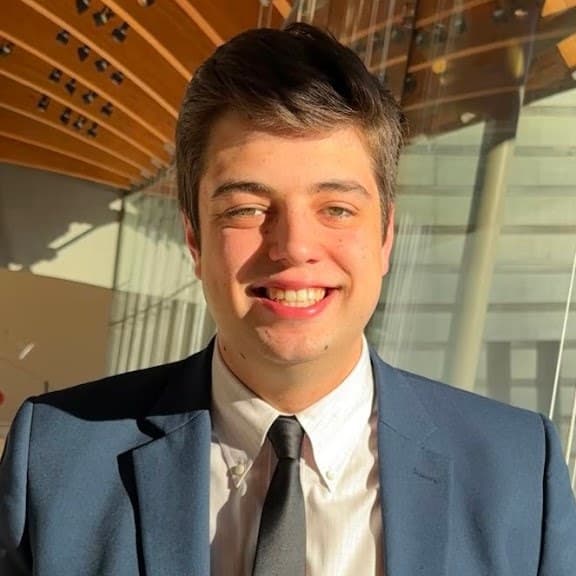 Noah Hertlein smiling in a navy suit
